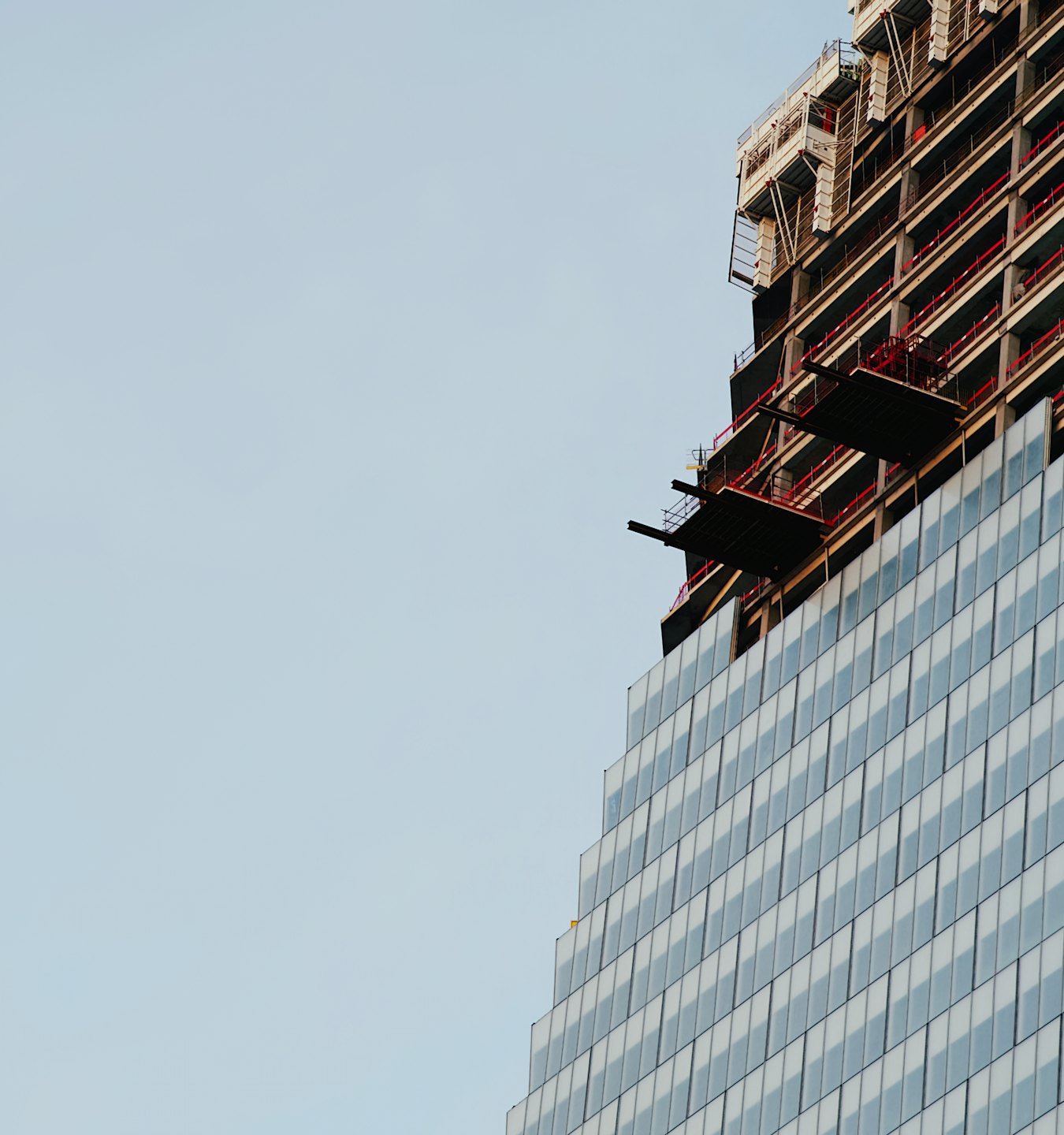 Modern glass skyscraper under construction with scaffolding.