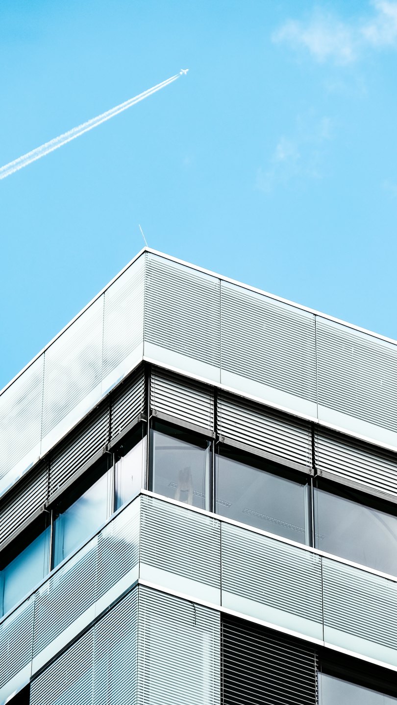 Modern office building with glass facade and blue sky.