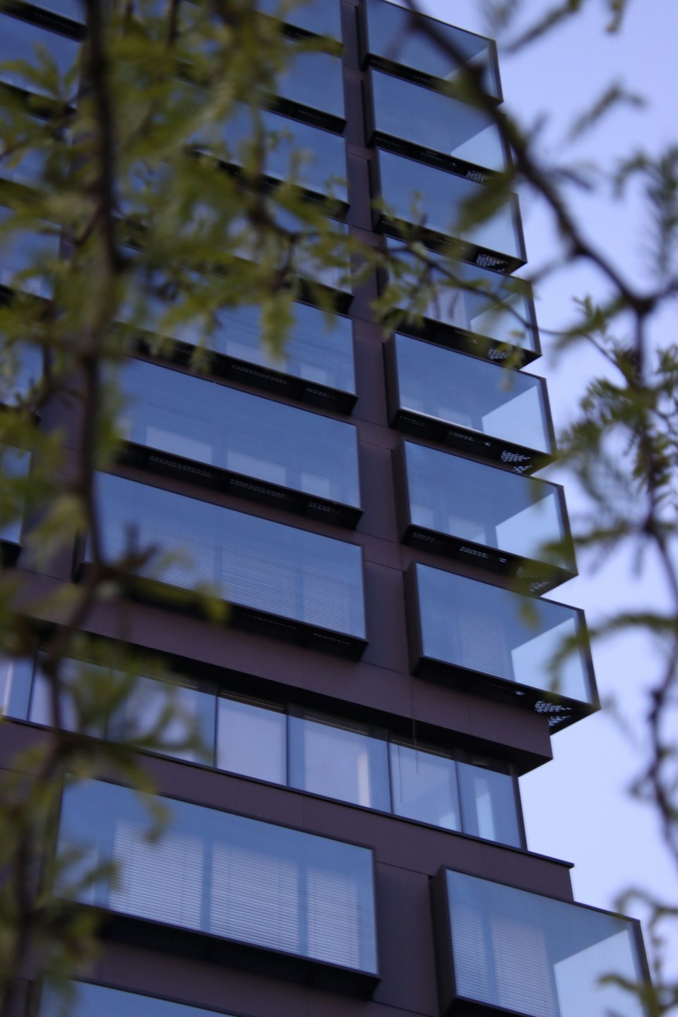 Modern building exterior with dark brown facade and glass balconies.